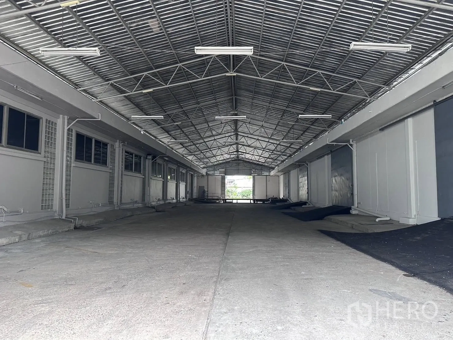 คลังสินค้า for rent in Mueang Samut Prakan, Samut Prakan - โถงโหลดสินค้าคลุมหลังคาโครงเหล็กยาว มีประตูม้วนหลายช่องภายในโกดัง