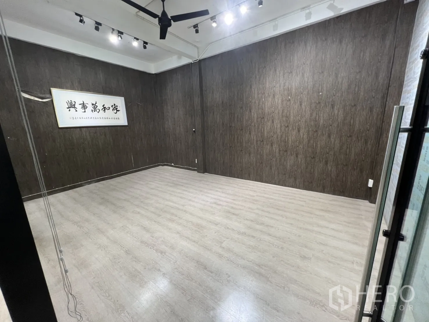 零售空间 出租在Watthana, Bangkok - 宽敞多功能房，深色纹理墙与浅色地面，顶置风扇。