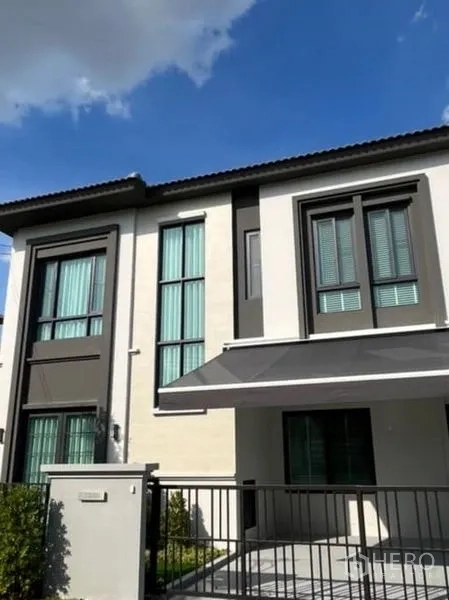 Detached House for rent or sale in Samut Prakan - Two-storey modern house facade with tall windows and carport awning.