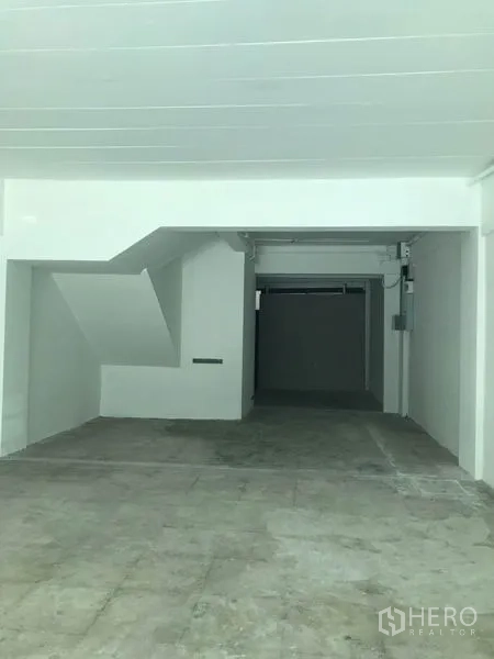 零售空间 出租在Watthana, Bangkok - 室内毛坯开间，白色墙面与混凝土地面，带楼梯下方空间，进深长。