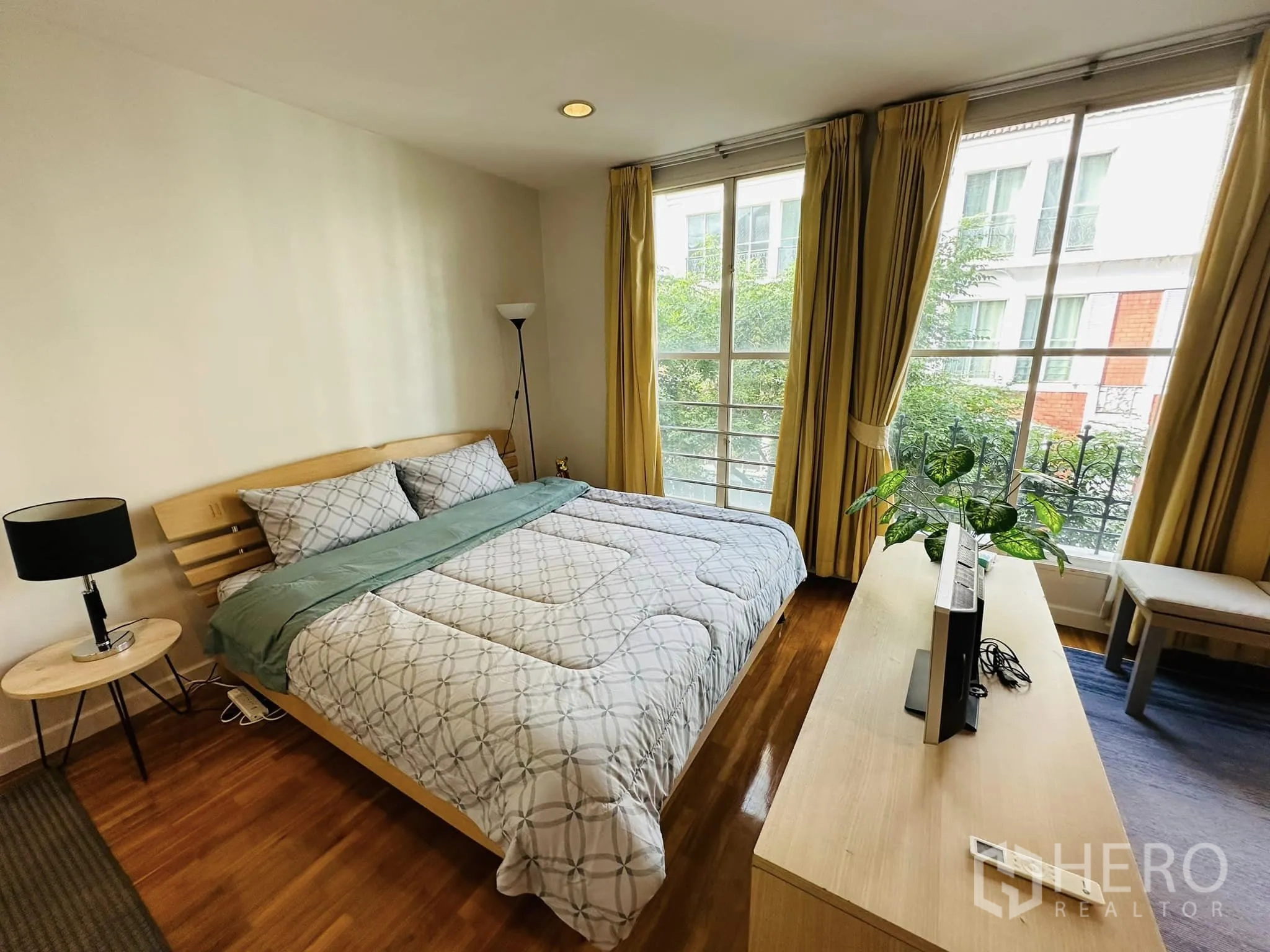 Townhouse for rent in Watthana, Bangkok - Guest bedroom with large windows, bed, TV console and indoor plant.