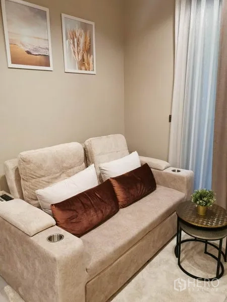 คอนโด ให้เช่าหรือขายในRatchathewi, Bangkok - มุมนั่งเล่นกะทัดรัด โซฟาสองที่นั่งนุ่ม โต๊ะข้าง และกรอบรูปติดผนัง