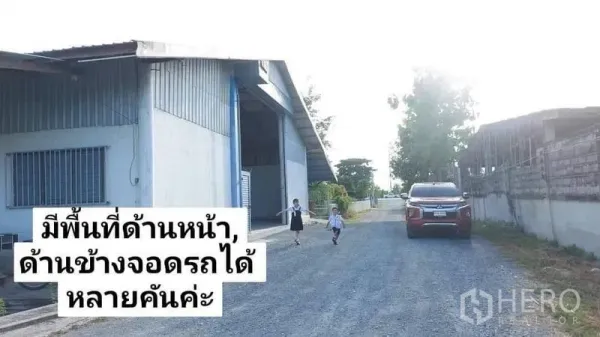货栈 出租在Nakhon Pathom - 仓库外立面与碎石道路，前方留有宽敞的多车位停车空间。