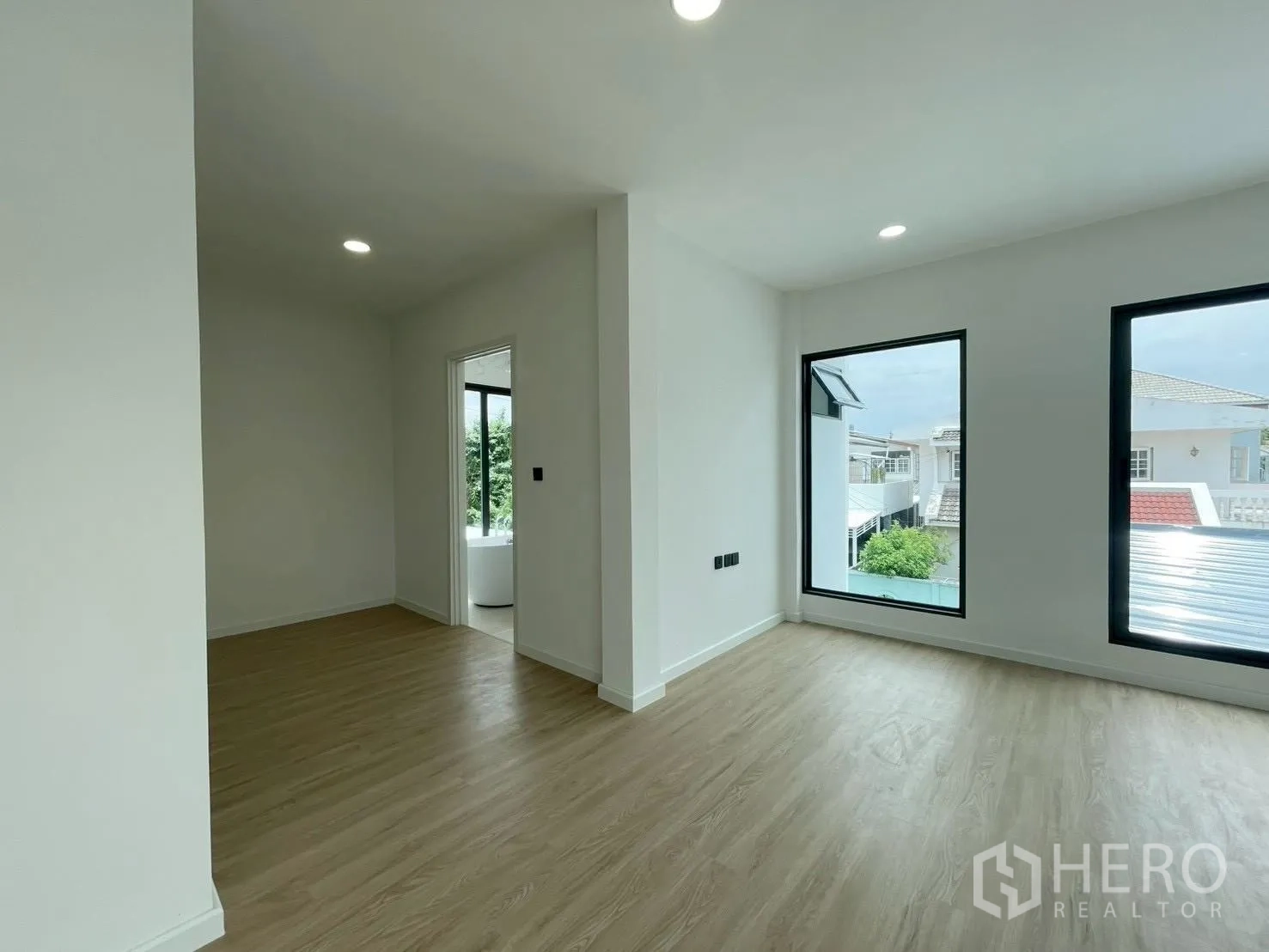 Detached House for sale in Chatuchak, Bangkok - Upper-level bedroom with wood floors, big windows, and doorway to an ensuite bathroom.