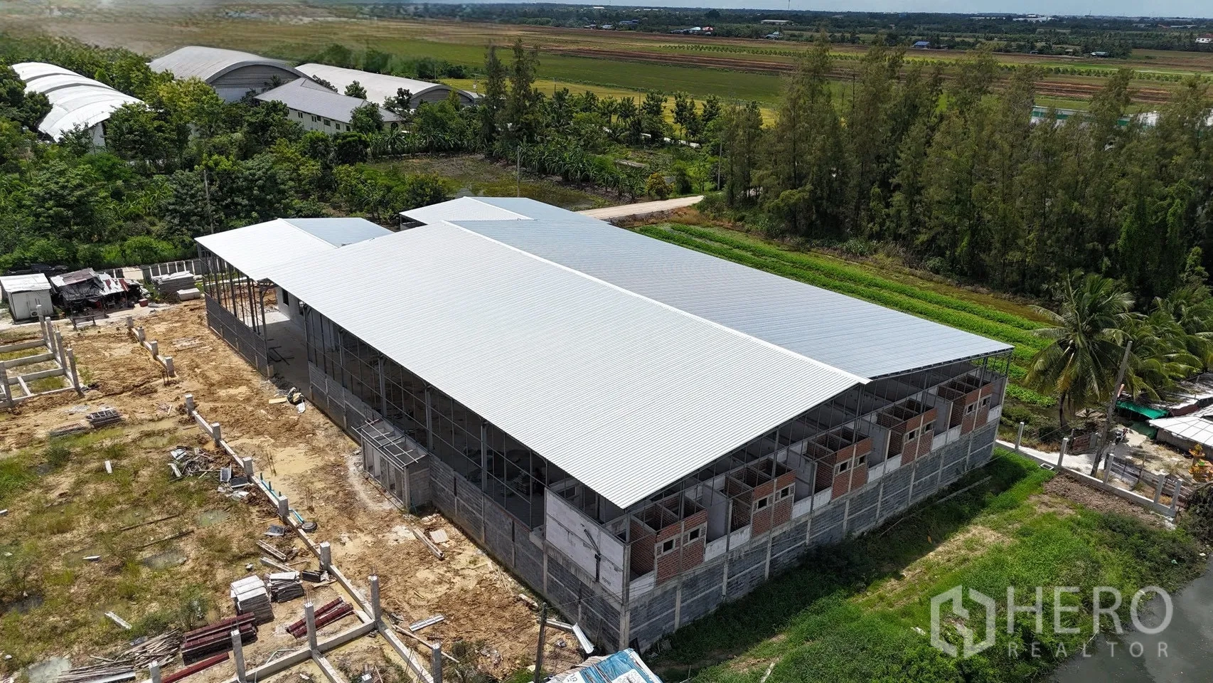 Factory for rent in Phutthamonthon, Nakhon Pathom - Aerial angle showing expansive metal‑roofed warehouse in a rural setting.