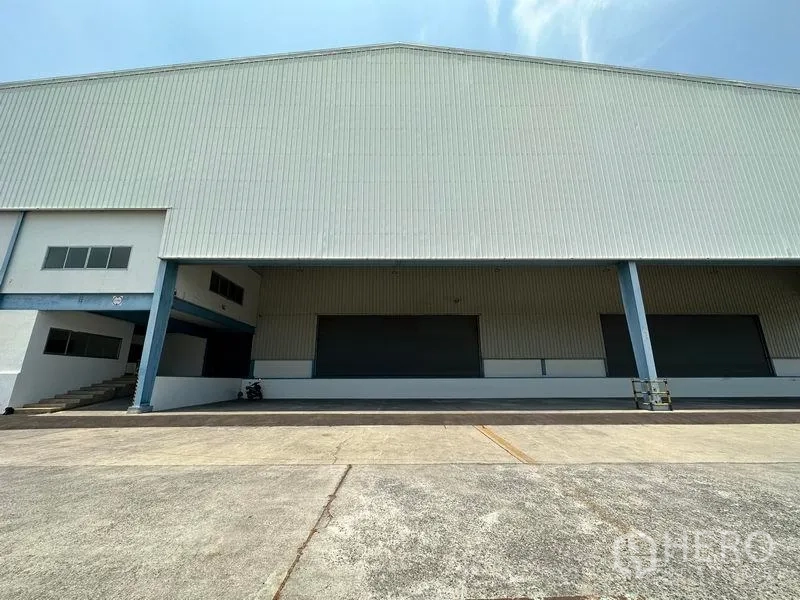 Warehouse for rent in Bang Phli, Samut Prakan - Wide covered loading bays with roller shutter doors and steel columns at the warehouse front.
