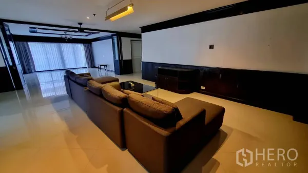 公寓 出租在Watthana, Bangkok - 宽敞客厅，转角沙发、电视柜与亮面地砖。