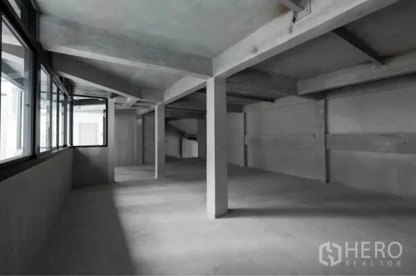 零售空间 出租在Watthana, Bangkok - 未装修的店铺内部，层高通透，承重柱与转角窗，便于自定义装修。