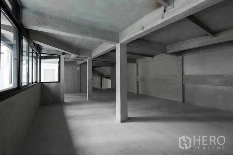 零售空间 出租在Watthana, Bangkok - 未装修的店铺内部，层高通透，承重柱与转角窗，便于自定义装修。