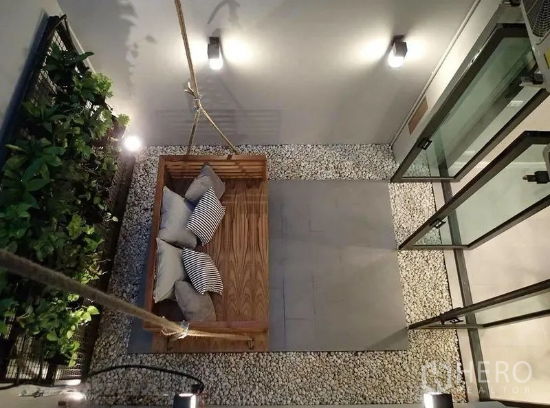 Townhouse for rent in Watthana, Bangkok - Internal courtyard with hanging wooden swing, pebble flooring, and vertical garden.