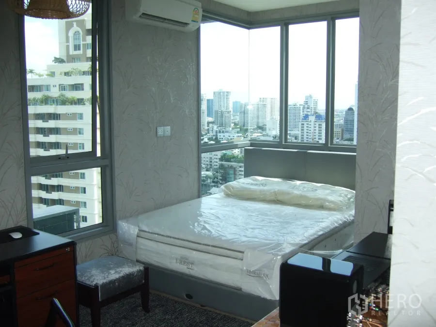 Condominium for rent or sale in Watthana, Bangkok - Corner bedroom with floor-to-ceiling windows and panoramic Bangkok skyline views.