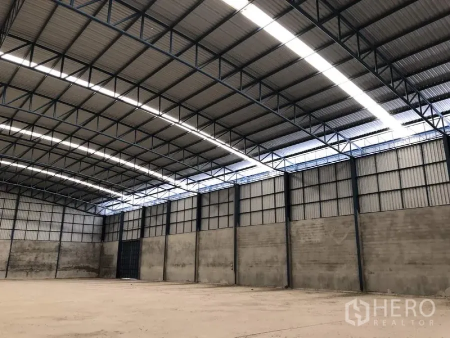 货栈 出租在Saraburi - 仓库内部，高钢结构拱形屋顶与采光带，平整的混凝土地面。