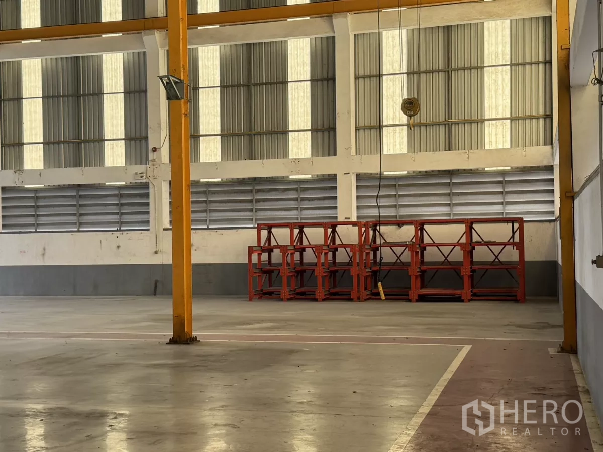 工厂 出租或出售在Bang Phli, Samut Prakan - 开阔生产区，吊钩与靠墙的红色钢制货架。