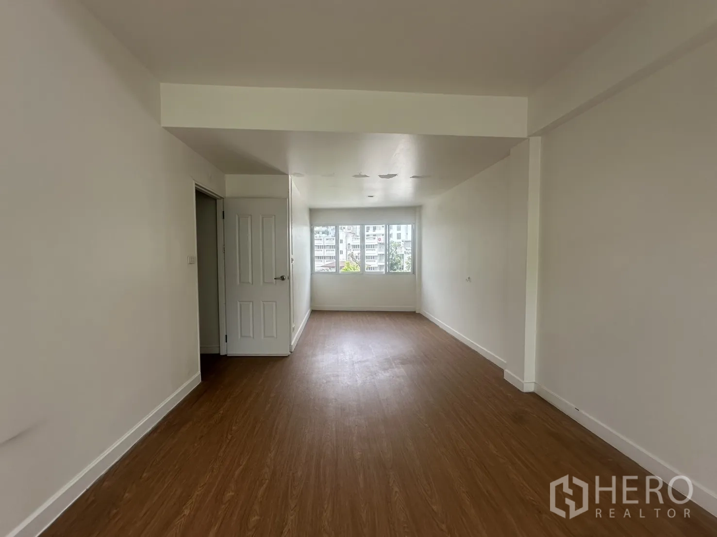 Home Office for rent in Watthana, Bangkok - Top-floor room with wood-look flooring and a window at the far end.