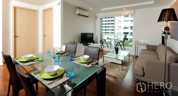 คอนโด ให้เช่าหรือขายในKhlong Toei, Bangkok - ห้องนั่งเล่นและรับประทานอาหารแบบโอเพ่นแปลน พร้อมโซฟา โต๊ะกระจก และระเบียงวิวเมืองในคอนโดสุขุมวิท