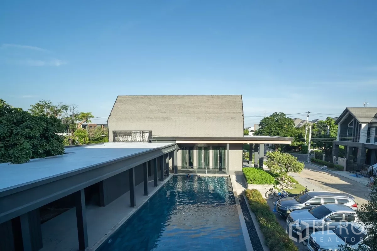 Detached House for rent in Saphan Sung, Bangkok - Clubhouse area featuring an outdoor swimming pool beside a modern pavilion and parking.