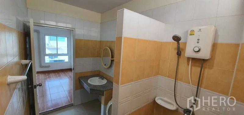 带办公室的家 出租在Prawet, Bangkok - 瓷砖浴室，配电热水器、淋浴、洗手台和镜子，带采光窗。