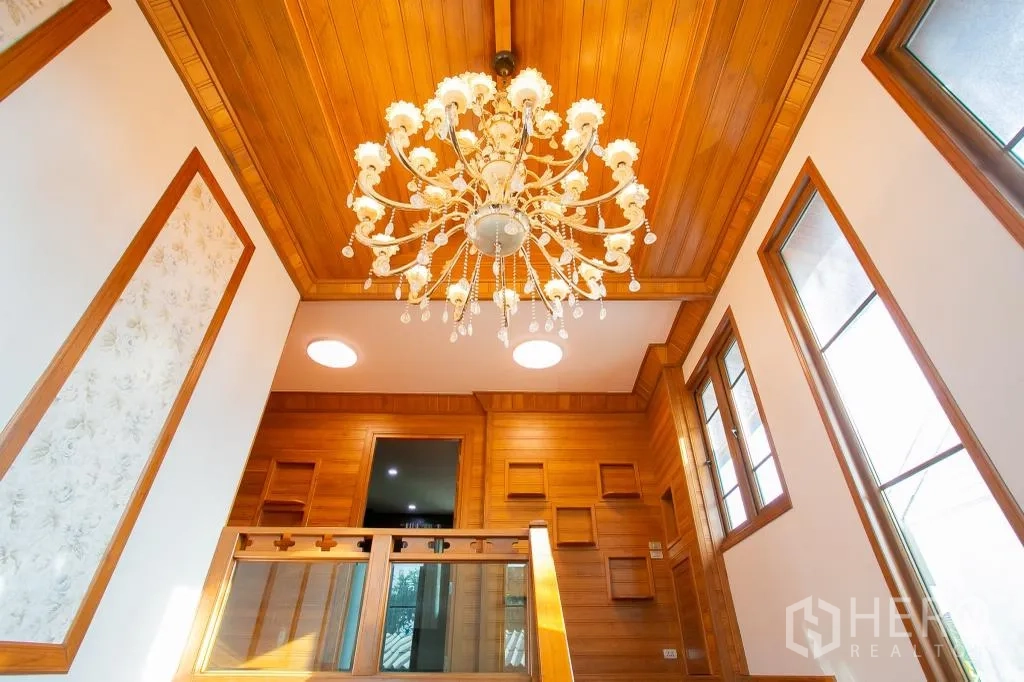 Detached House for rent or sale in Huai Khwang, Bangkok - Grand chandelier above stairwell beneath a warm wood ceiling and tall windows.
