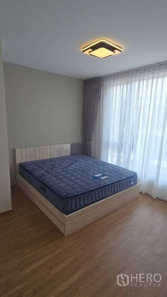 Townhouse for rent in Bang Phli, Samut Prakan - Master bedroom with wood flooring, large window and upholstered bed.