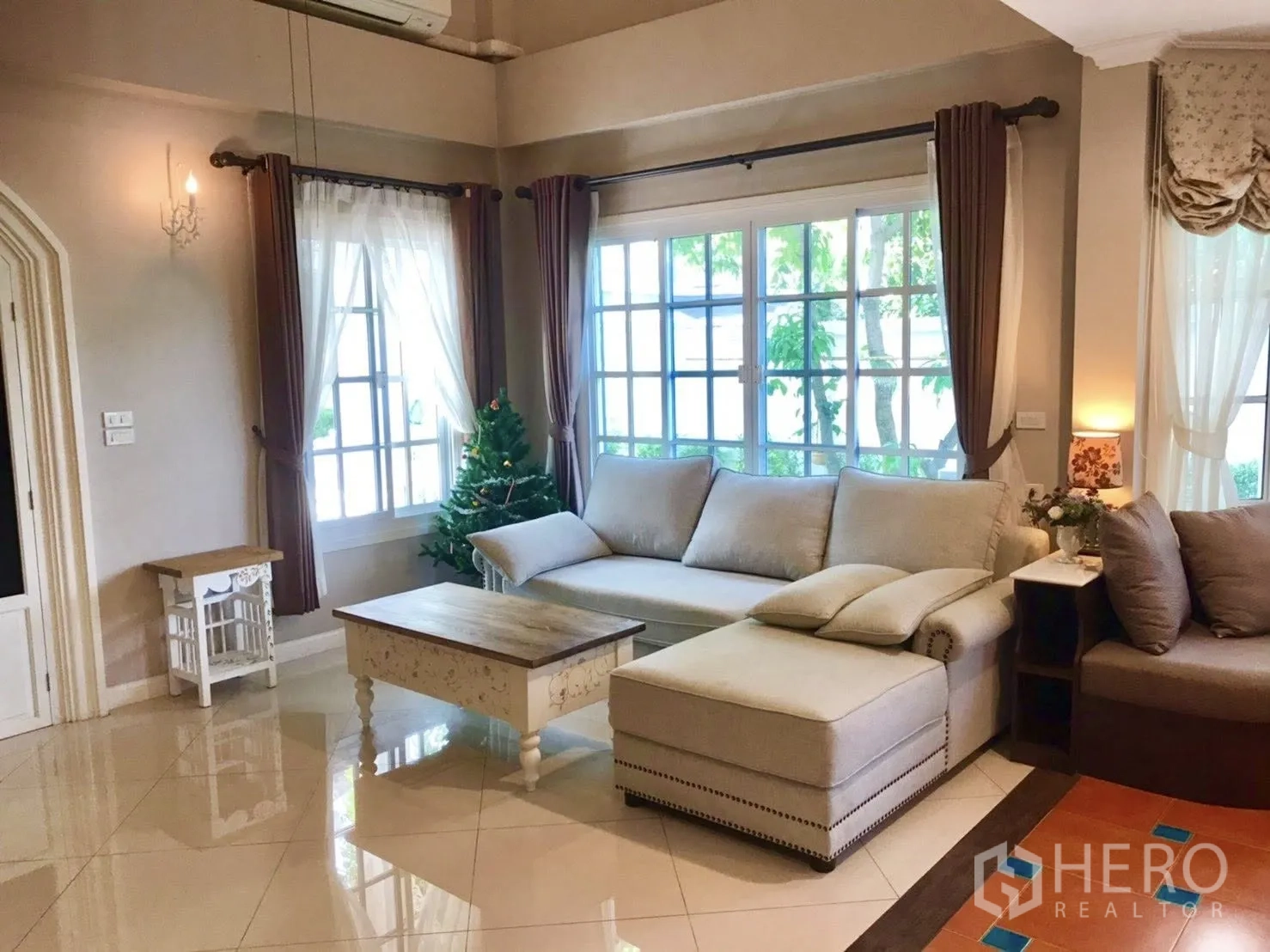 Detached House for rent in Mueang Samut Prakan, Samut Prakan - Cozy living area with L-shaped sofa, coffee table and large curtained windows.