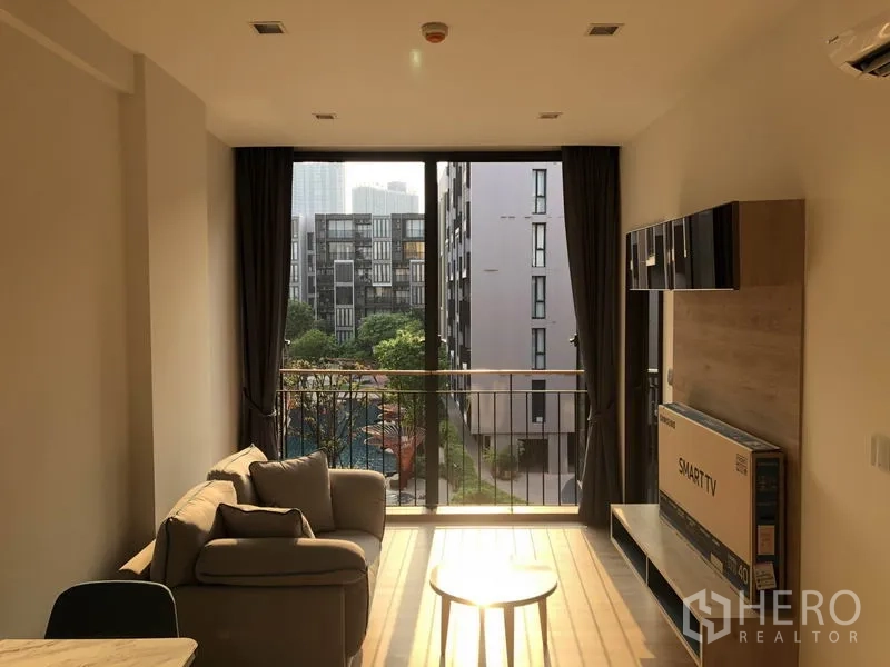 คอนโด ให้เช่าในWatthana, Bangkok - พื้นที่นั่งเล่นมีหน้าต่างจรดเพดานและระเบียง มองเห็นสวนและสระว่ายน้ำ