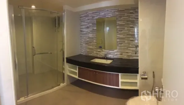 Condominium for rent or sale in Chatuchak, Bangkok - Modern bathroom with glass-enclosed shower, long vanity, and mosaic tile backsplash.