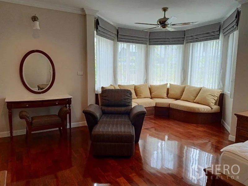 独立式住宅 出租在Bang Na, Bangkok - 起居室设弧形飘窗坐榻、扶手椅与亮泽木地板。