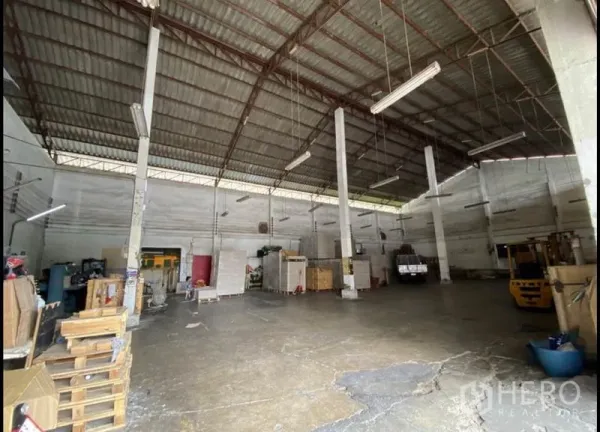 Warehouse for rent in Bang Khun Thian, Bangkok - Spacious warehouse interior with high steel-truss roof, concrete floor, and hanging fluorescent lights for storage and operations.