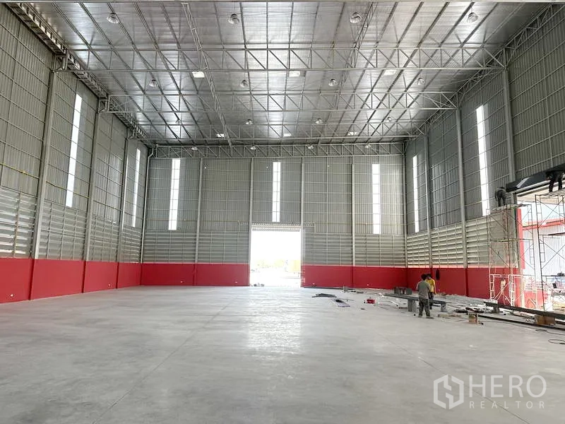 Warehouse for rent in Khlong Luang, Pathum Thani - Warehouse interior facing the loading door with high-bay lighting and expansive floor area ready for racking or staging.