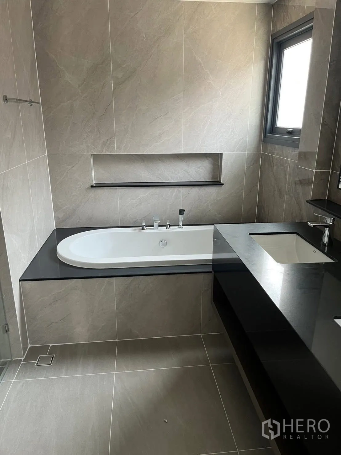Detached House for rent in Bang Phli, Samut Prakan - Modern bathroom with built-in bathtub, gray stone tiles, and window.