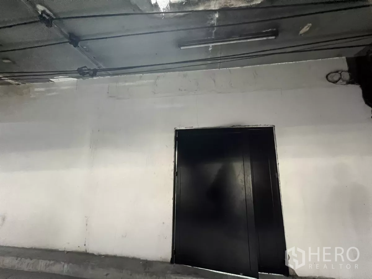 店屋 出售在Suan Luang, Bangkok - 高架桥下黑色金属双门特写，顶部管线清晰可见。