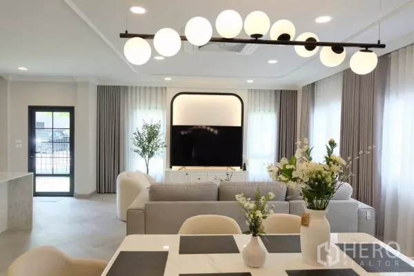 Detached House for sale in Bang Phli, Samut Prakan - Dining area with globe pendant light and flowers, looking toward the living room and large windows