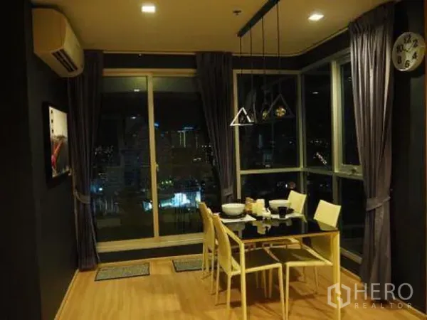 Condominium for rent in Sathon, Bangkok - Corner dining area with glass table and pendant lights beside large windows and city lights in Bangkok.