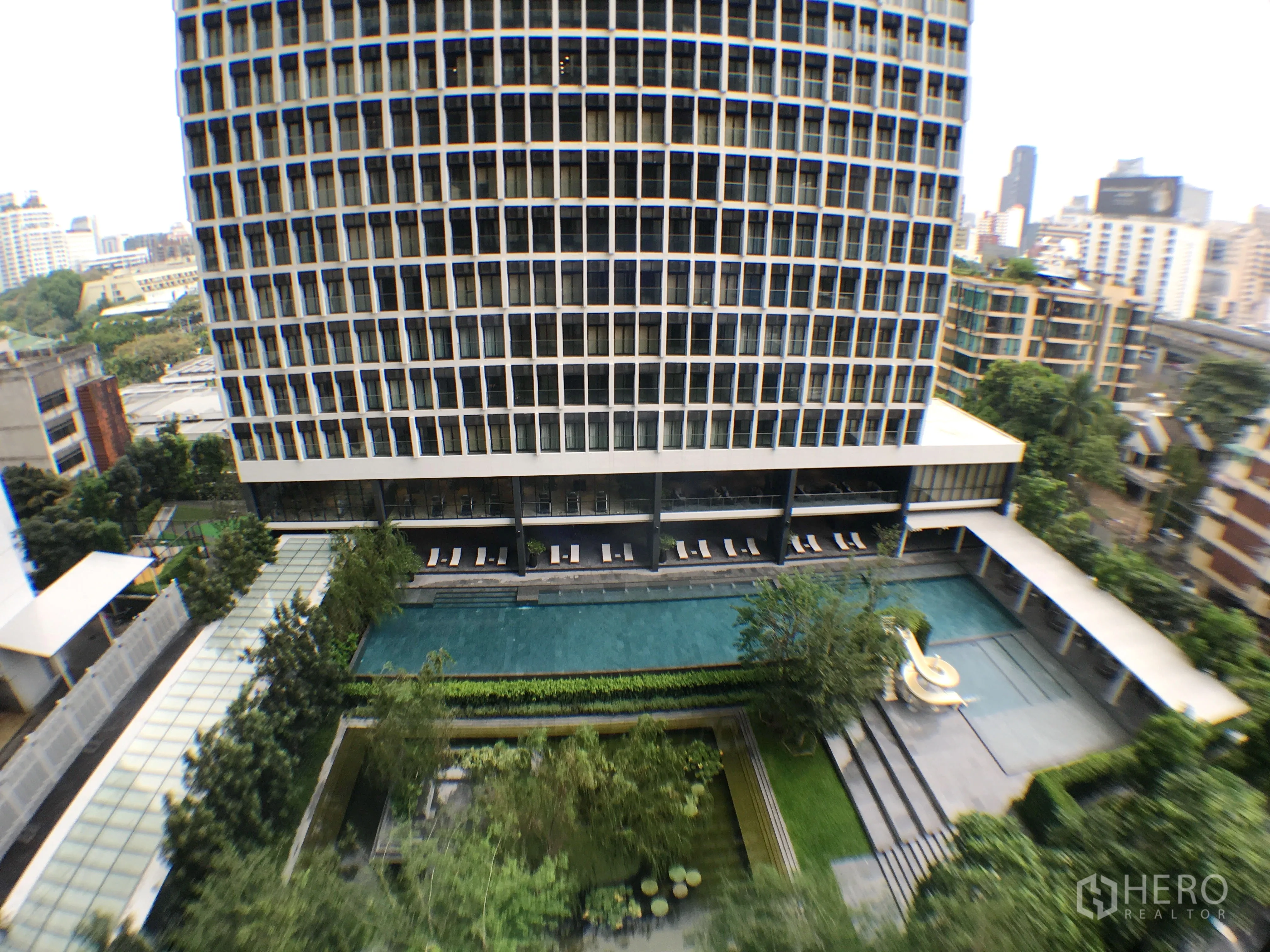 Condominium for rent in Pathum Wan, Bangkok - High-rise condo view overlooking landscaped pool, gardens and city skyline.