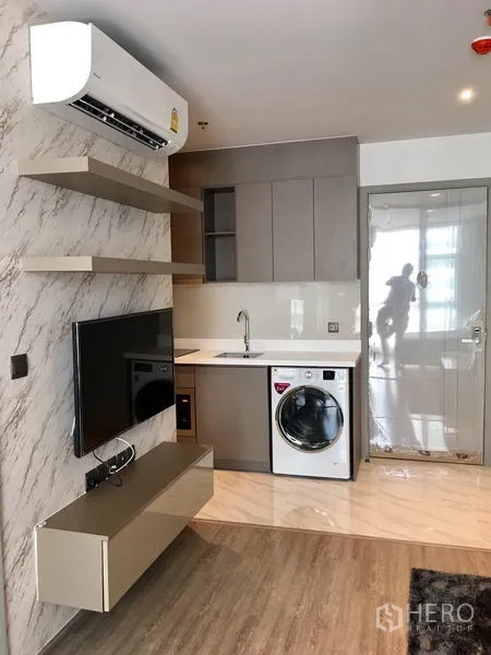 Condominium for rent in Watthana, Bangkok - Entry to a kitchenette with marble-look wall, sink and front-loading washer.