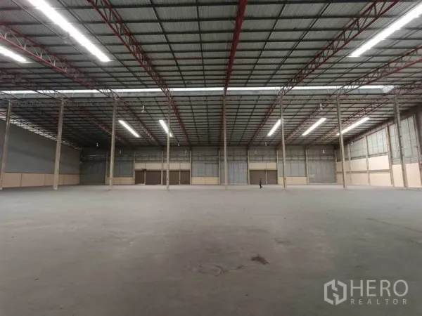 工厂 出租在Samut Prakan - 开阔工业大厅，立柱排列、金属屋面与长条照明，适合生产或仓储使用。