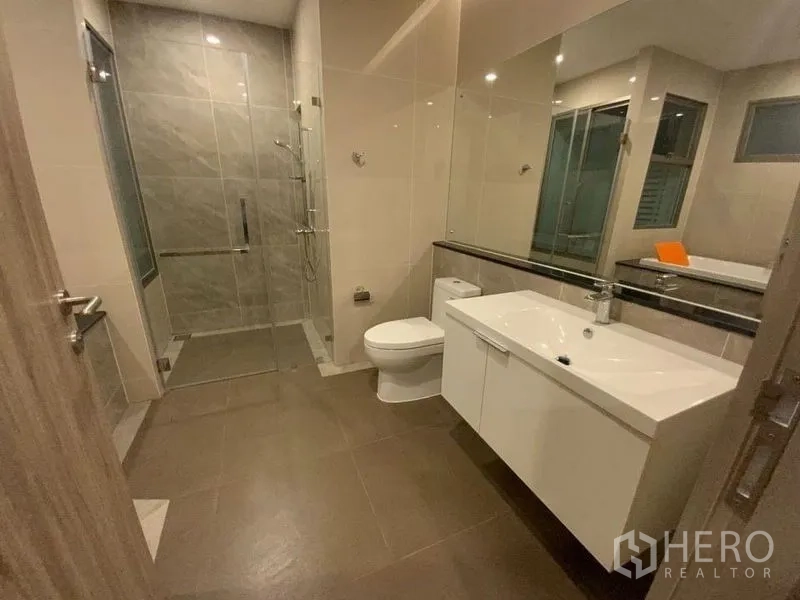 联排别墅 出租在Prawet, Bangkok - 宽敞浴室，带洗手台、坐厕与玻璃淋浴间。