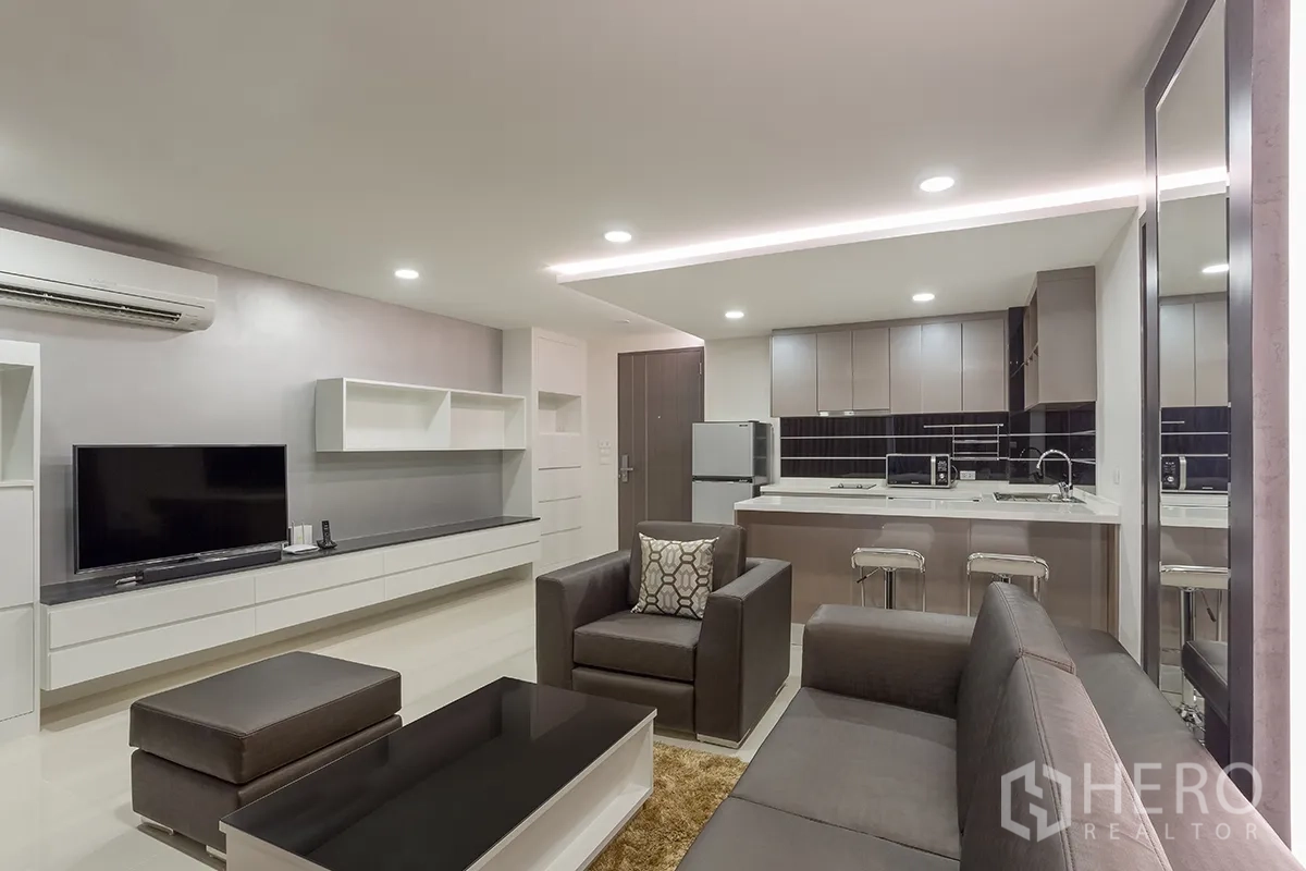 คอนโด for rent in Khlong Toei, Bangkok - โถงนั่งเล่นแบบเปิดโล่งพร้อมโซฟาชุด ชั้นวางทีวีบิวท์อิน และครัวเชื่อมต่อ