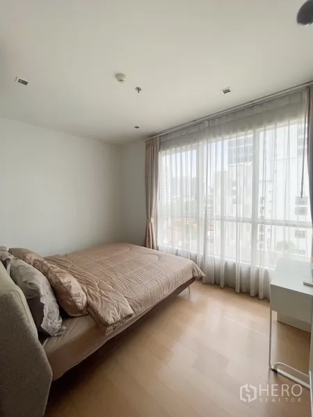 Condominium for rent in Watthana, Bangkok - Sunlit bedroom with large windows, double bed and city outlook.