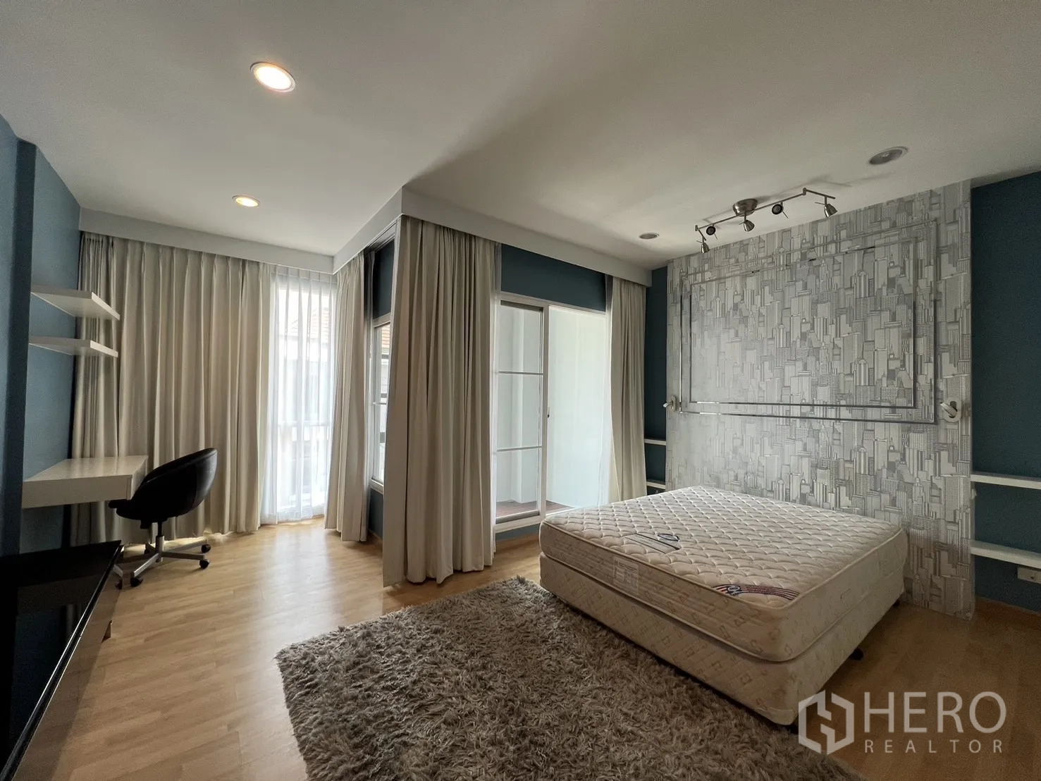 Townhouse for rent in Wang Thonglang, Bangkok - Master suite with study desk, rug and floor-to-ceiling curtains.