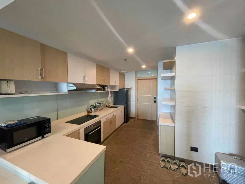 Condominium for rent in Sathon, Bangkok - Fully equipped galley kitchen with white countertops, oven, cooktop, hood and ample upper and lower cabinets.