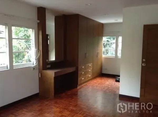 Detached House for rent in Ratchathewi, Bangkok - Bedroom with parquet flooring, corner windows and built-in wardrobe and dressing desk.