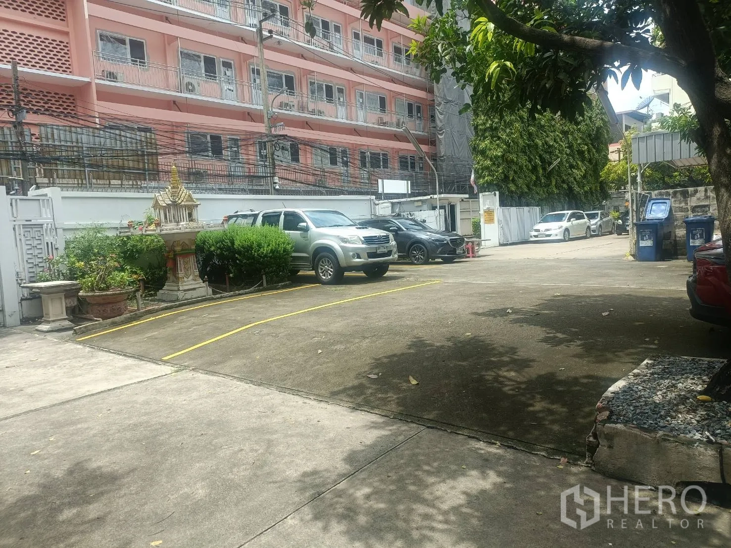 Detached House for rent in Bang Rak, Bangkok - Expansive paved parking courtyard with marked bays and a secure gate, urban surroundings.