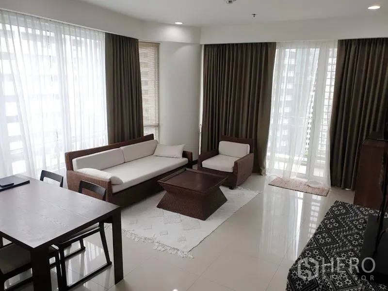 คอนโด ให้เช่าหรือขายในPathum Wan, Bangkok - ห้องนั่งเล่นสว่างด้วยผนังกระจกเต็มบาน ชุดโซฟาโทนครีม และทางออกสู่ระเบียง