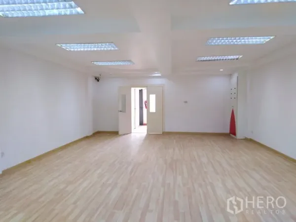 Office Space for sale in Bang Kapi, Bangkok - Open-plan office room with wood floors and double doors under recessed grid lights.