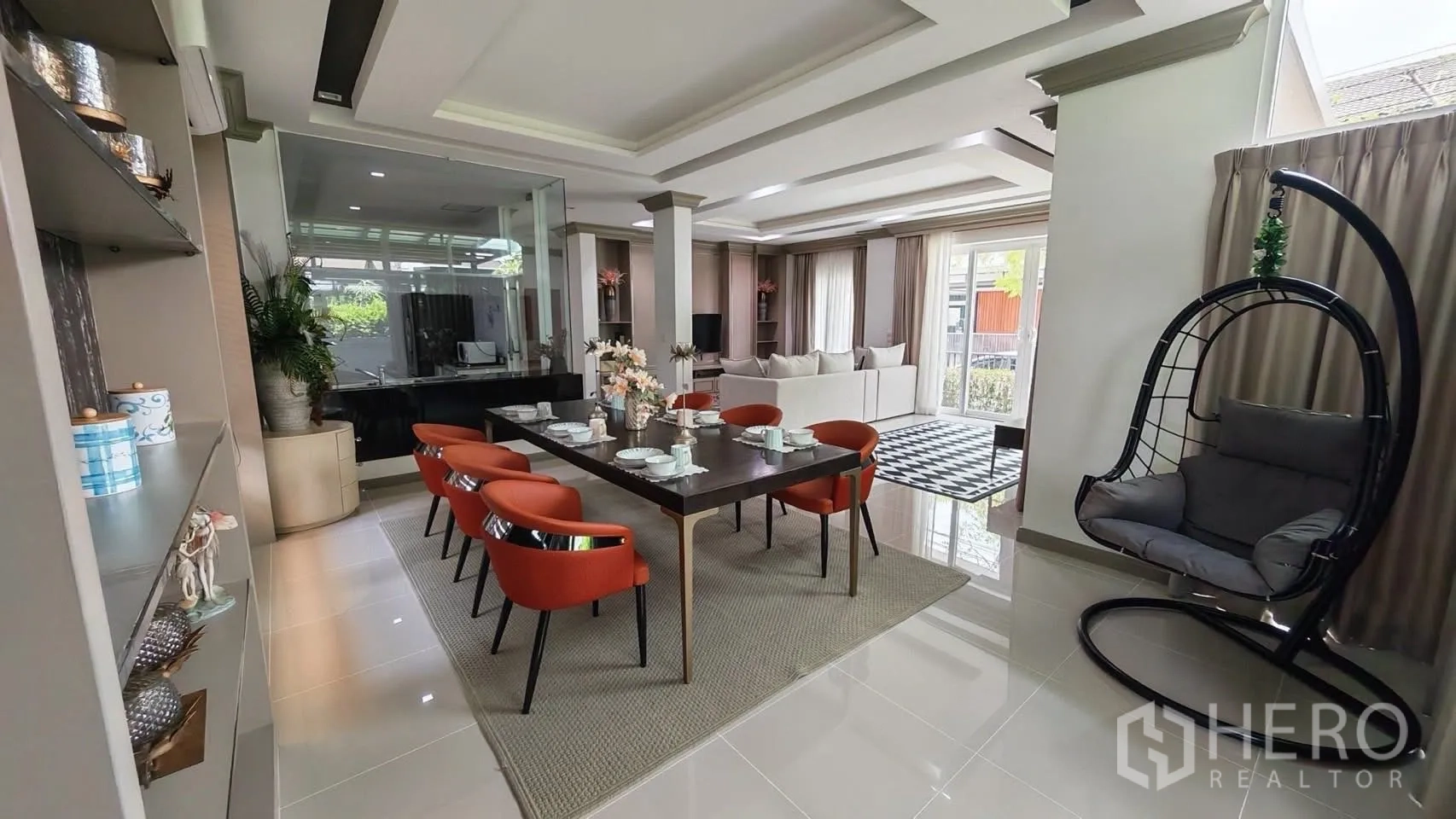 Detached House for rent or sale in Bang Phli, Samut Prakan - Dining area set for eight with orange chairs and a hanging egg chair beside the window.