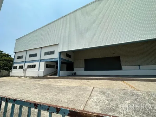 Warehouse for rent in Bang Phli, Samut Prakan - Corner view showing the attached office block, external stairs, and the main loading dock under a canopy.