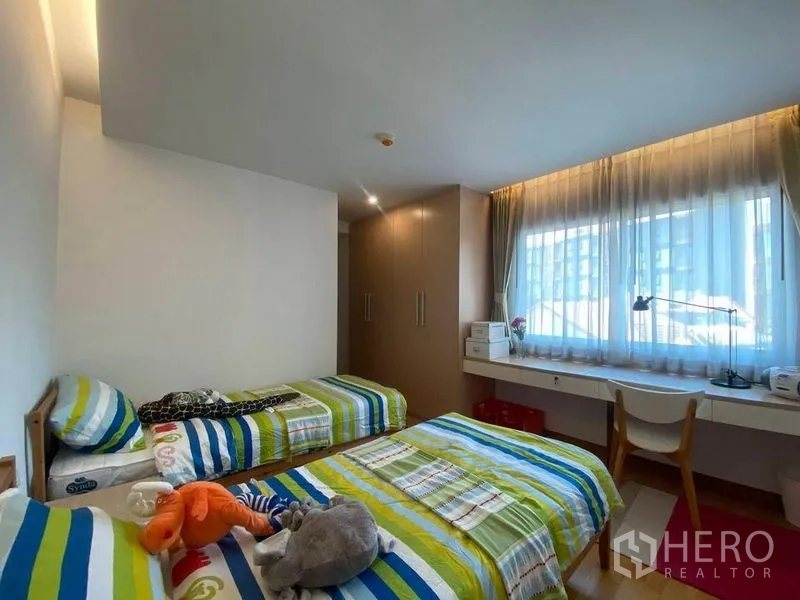 公寓 出租或出售在Phra Khanong, Bangkok - 采光充足的双床卧室，配两张单人床、大窗、长书桌和内置衣柜。