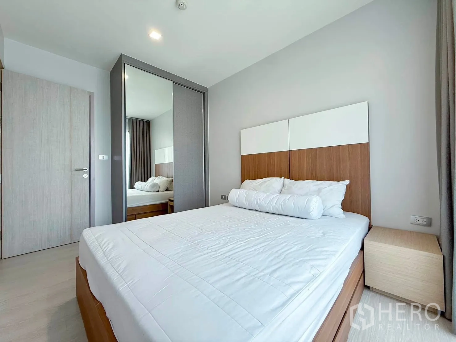 Condominium for rent in Khlong Toei, Bangkok - Bright bedroom with double bed, mirrored wardrobe, and bedside table.