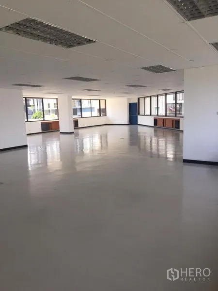 Office Space for rent in Bang Kapi, Bangkok - Spacious bright office area with wide perimeter windows, polished flooring and a blue entry door.